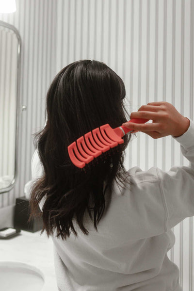 Brunette woman brushing her hair, showing the gentle detangling of the zig-sag shaped Tangle Buster Super flex brush.