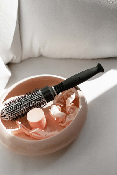 Small Ionic thermal round brush in a trinket bowl with a pink scrunchie and hair barrette.