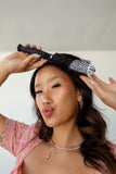 Young woman making a kissy face while styling her bangs with the small ionic thermal round brush.