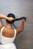 Lady detangling wet hair with the comb to create sleek ponytail.